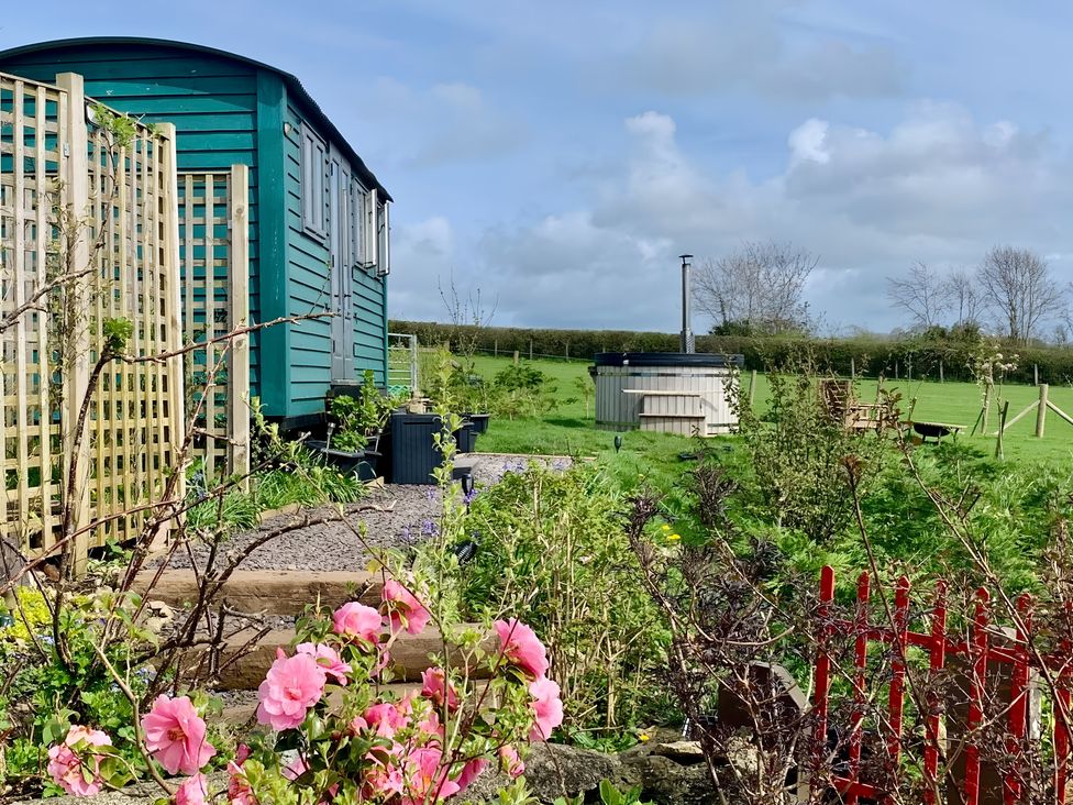 An outdoor area with a shepherd's hut and a hot tub at Bluebell Shepherd’s Hut in Llanfairpwllgwyngyll