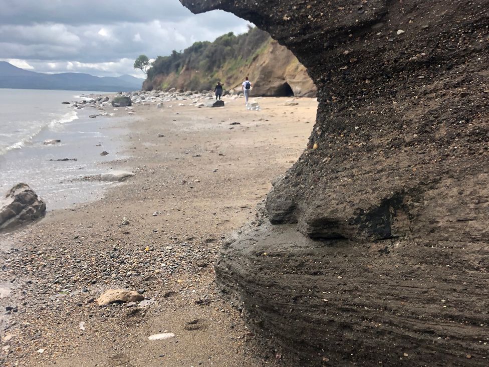 A beach with rocks and water at the shoreline near Llanfairpwllgwyngyll