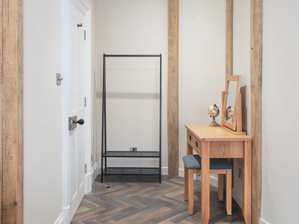 An entryway with a clothing rack and a desk with a mirror at Apt.1