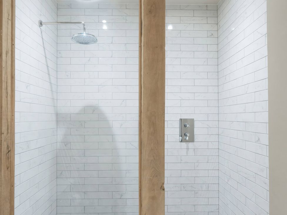A shower area with white tiles and a showerhead at Apt.1 in 