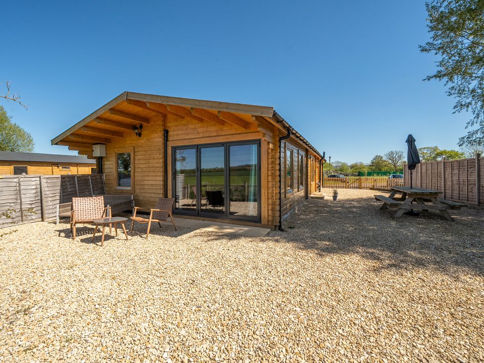 A wooden cabin with outdoor seating area at Cotswold Nights Ashton Under Hill