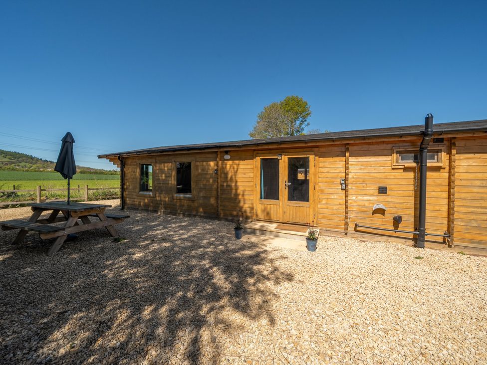 An outdoor area with a wooden cabin and a picnic table at Cotswold Nights Ashton Under Hill