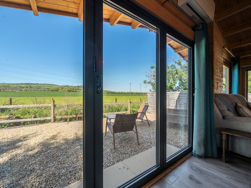 A living room with glass doors leading to a garden at Cotswold Nights in Ashton Under Hill