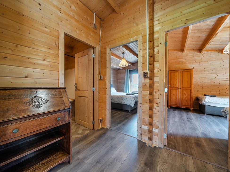 An interior view of a wooden bedroom with doors and furniture at Cotswold Nights Ashton Under Hill
