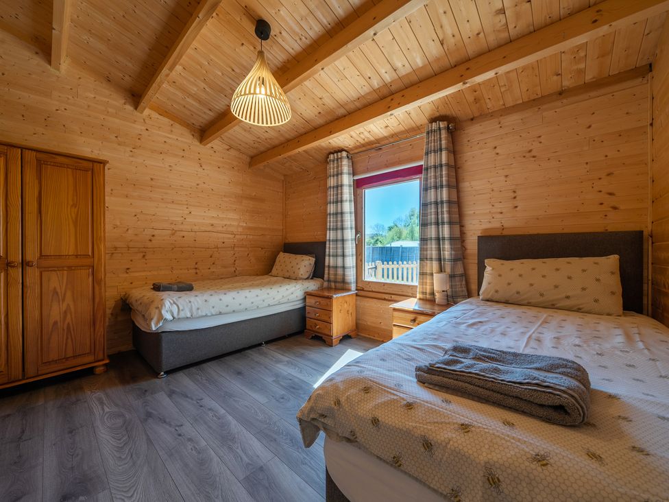 A bedroom with two beds and a wardrobe at Cotswold Nights Ashton Under Hill
