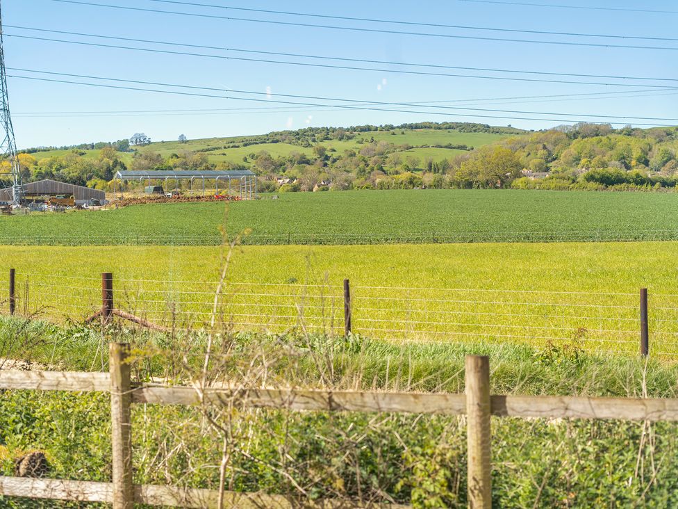 A farming field with buildings and hills in the background at Cotswold Nights Ashton Under Hill
