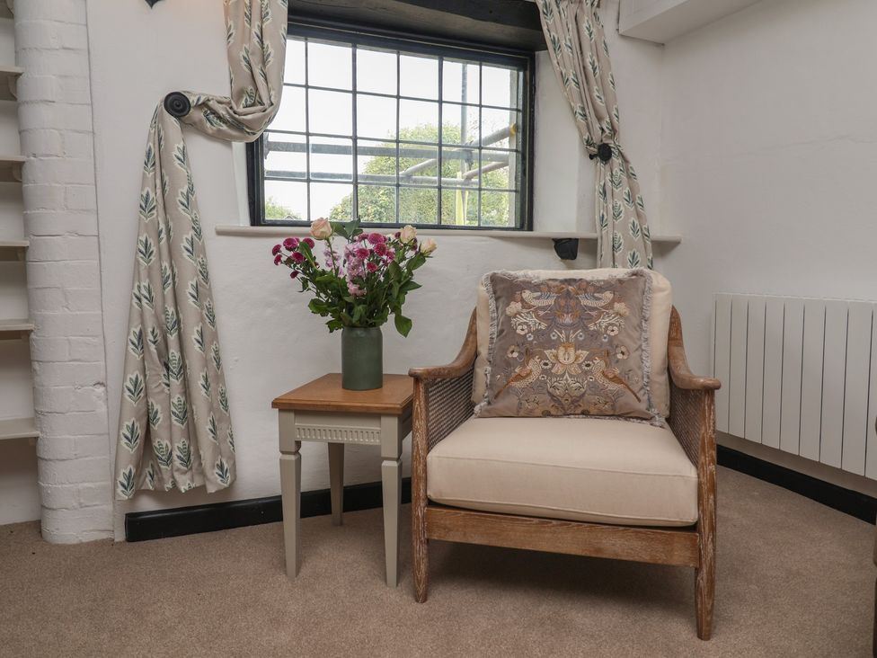 A snug with a chair, table and flowers at The Olde Forge Minehead