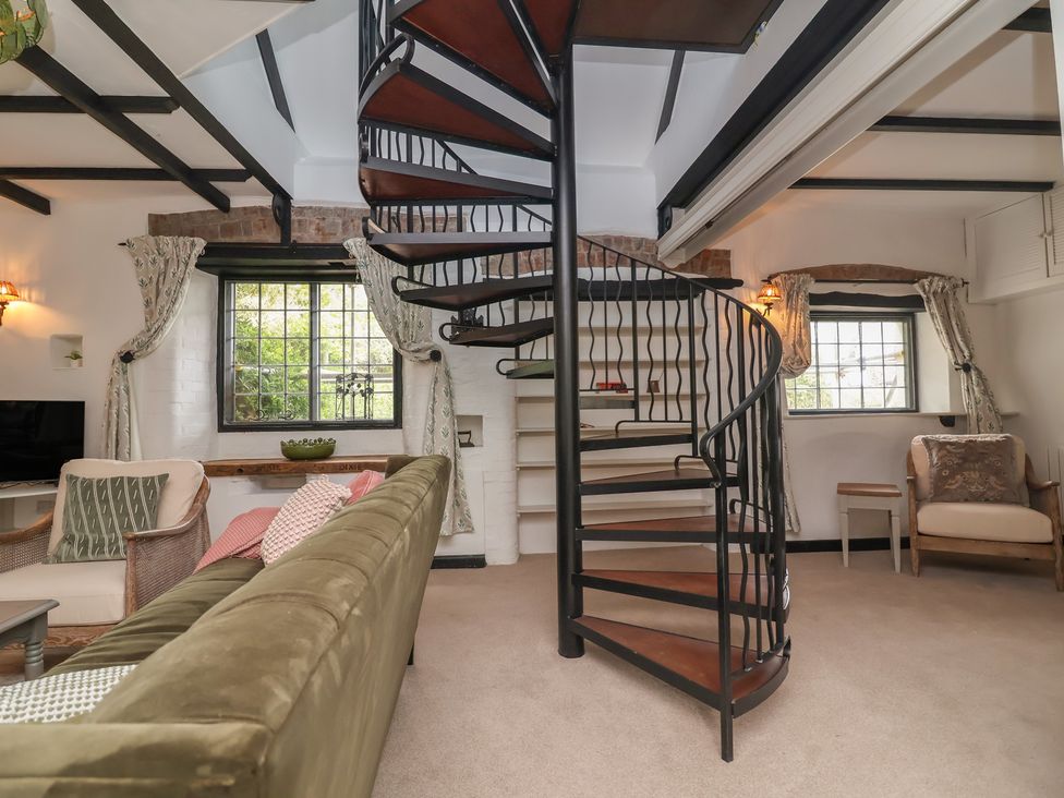 A living room with a spiral staircase and a sofa at The Olde Forge in Minehead