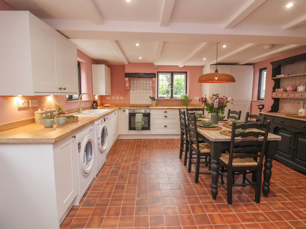 A kitchen with washing machine, sink, and dining table at The Olde Forge in Minehead