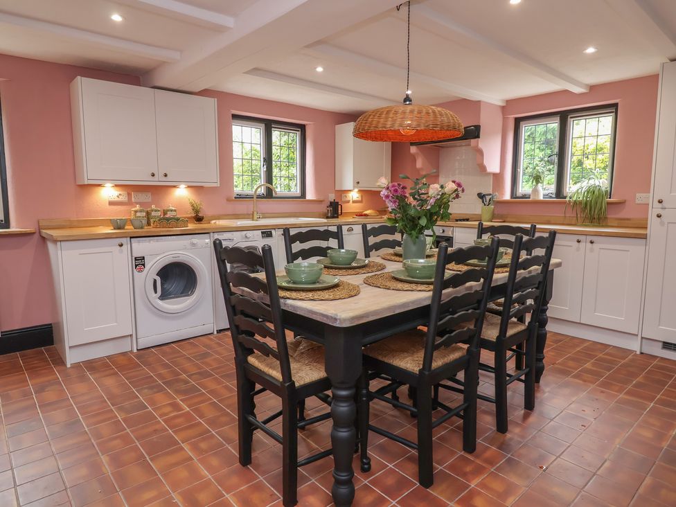 A kitchen with a dining table and washing machine at The Olde Forge in Minehead
