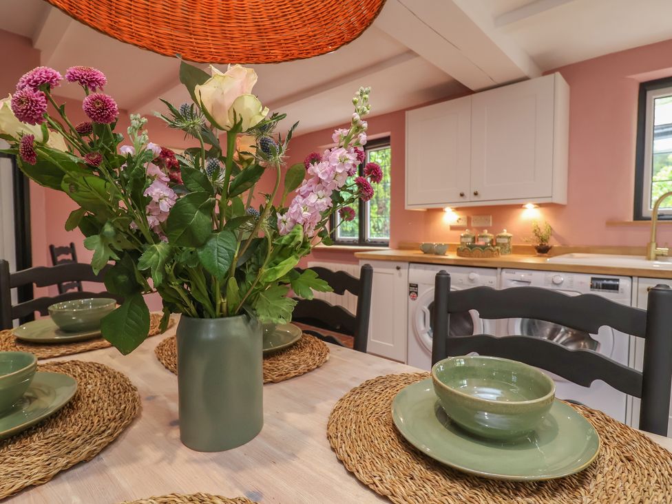 A dining room with a table set and flowers on the table at The Olde Forge in Minehead