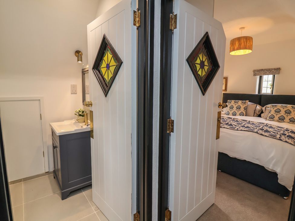 A bathroom with a sink and cabinet next to a bedroom at The Olde Forge in Minehead