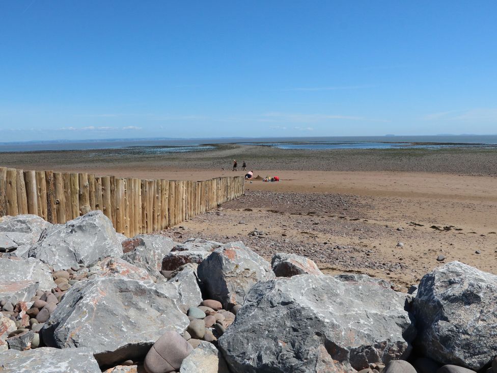 A beach with rocks and a wooden fence at The Olde Forge in Minehead