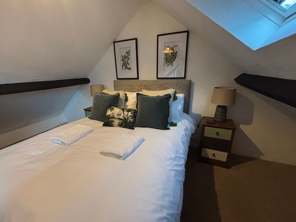 A bedroom with a bed, nightstand, and artwork at The Olde Forge in Carhampton near Minehead
