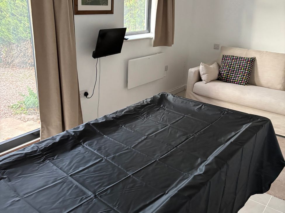 A living room with a table covered in black cloth and a sofa at The Olde Forge in Carhampton near Minehead