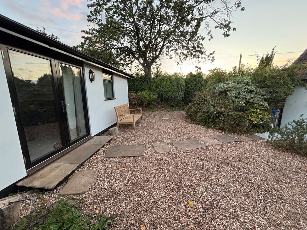 An outdoor area with a gravel pathway and a bench at The Olde Forge in Carhampton near Minehead