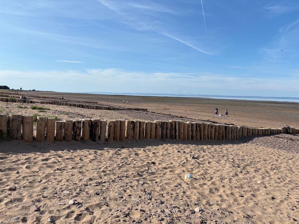 A beach with wooden posts and people walking at The Olde Forge in Carhampton near Minehead