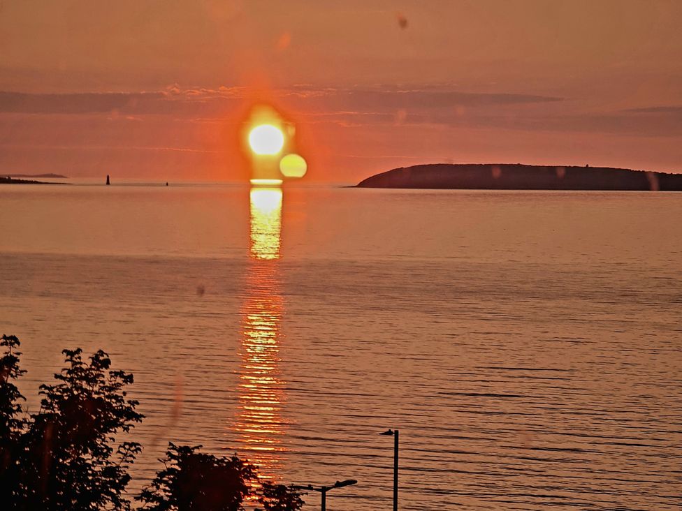 A sunset over the water with an island at Sea view cottage in Penmaenmawr
