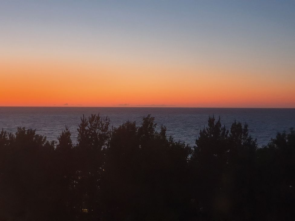 An ocean view with trees during sunset at Sea view cottage in Penmaenmawr
