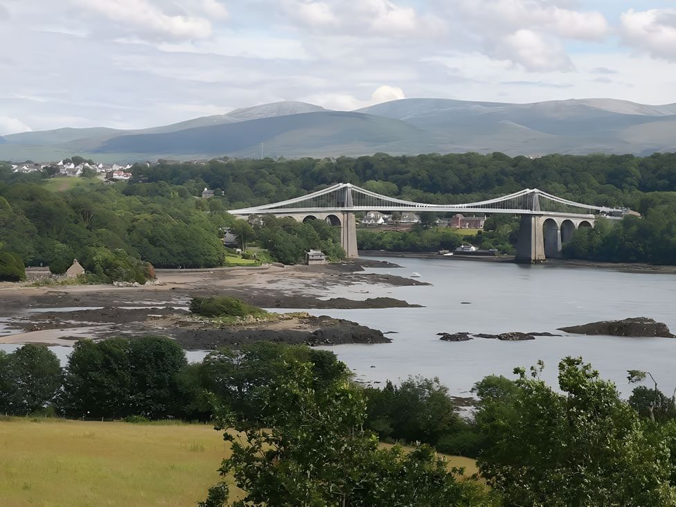 A view of a bridge over a river surrounded by trees and mountains at Sea view cottage in Penmaenmawr