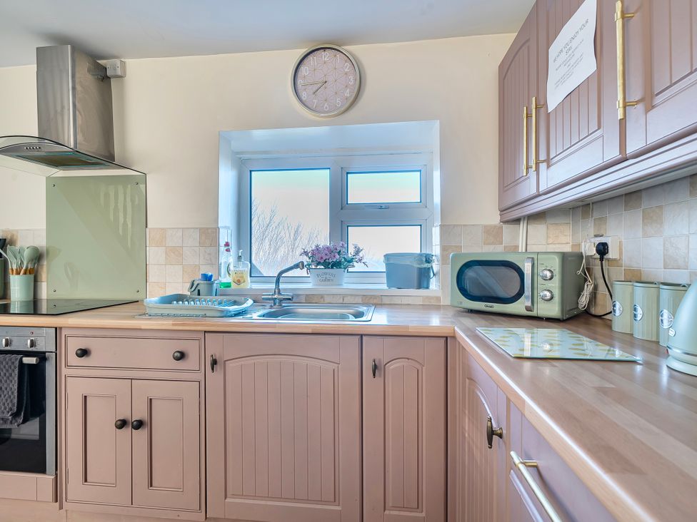 A kitchen with a sink and microwave at Sea view cottage in Penmaenmawr