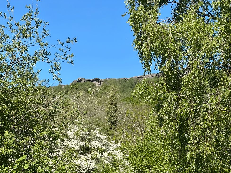 A view of trees and a rock formation under a blue sky at Hope Valley - Studio, Hope Valley