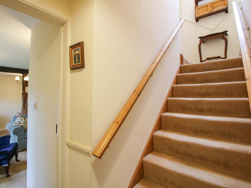 A staircase and hallway with a table and picture at Cardington 25 