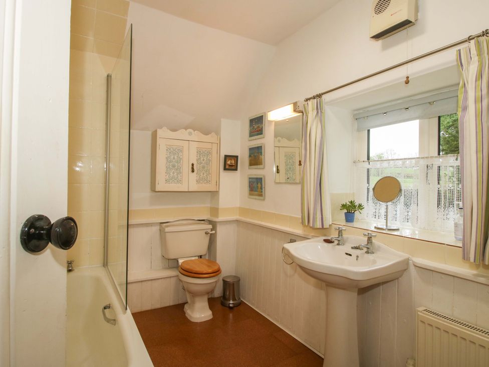 A bathroom with a bathtub, toilet, sink, and window at Cardington 25