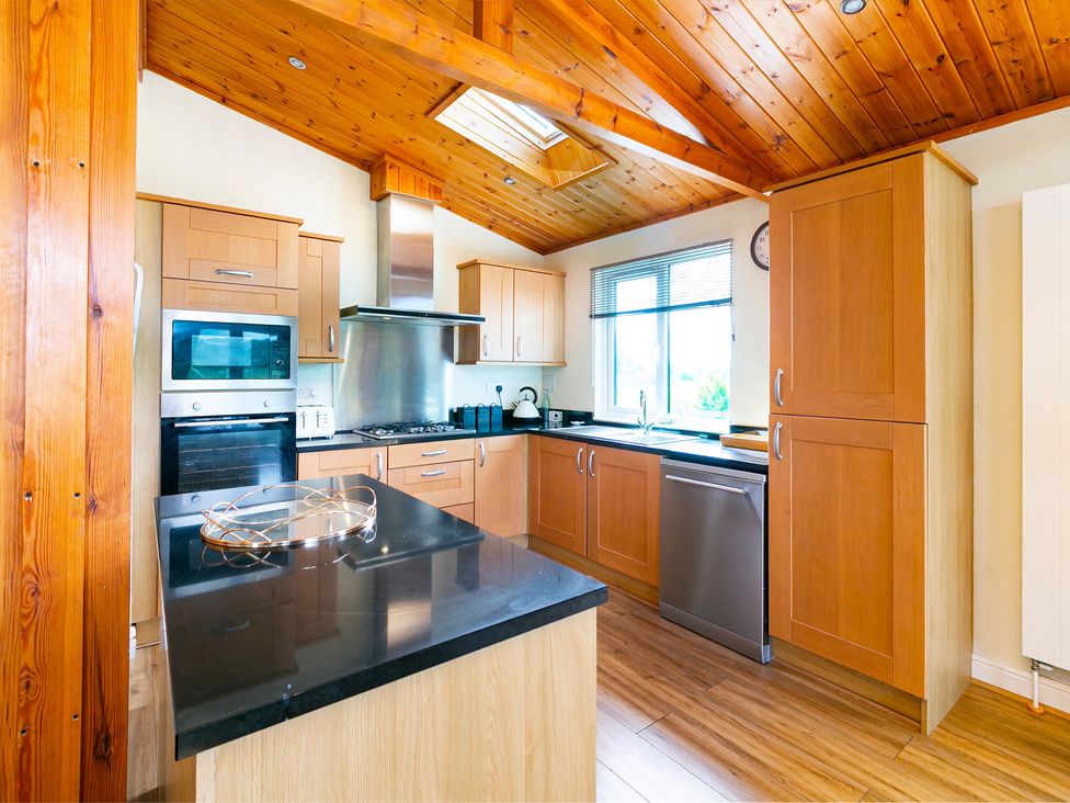 A kitchen with cabinets and appliances at Hedgehog Lodge in York