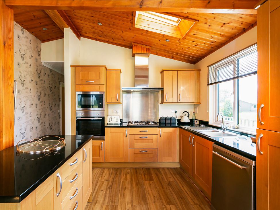 A kitchen with wood cabinets and appliances at Hedgehog Lodge in York