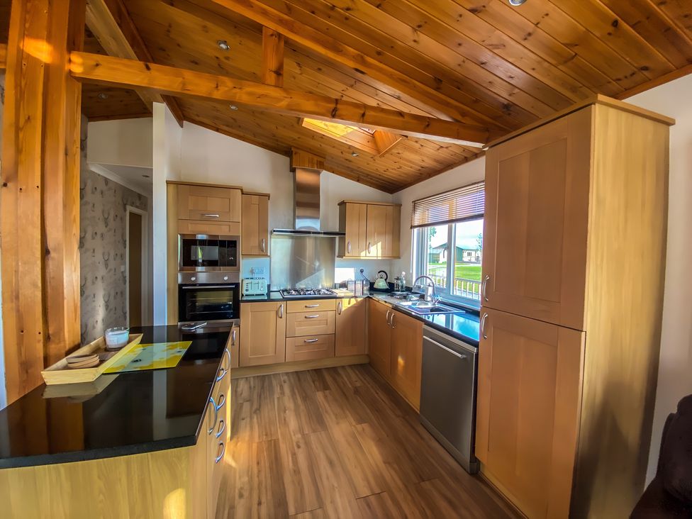 A kitchen with cabinets and appliances at Hedgehog Lodge in York