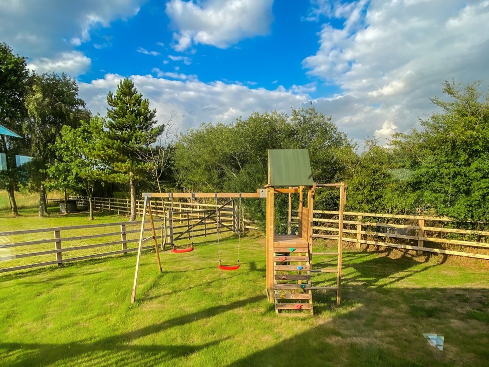 A swing set and slide in an outdoor area at Hedgehog Lodge in York