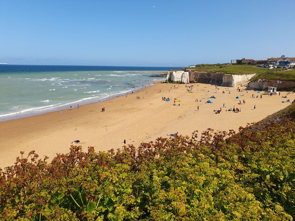A beach with people sunbathing and cliffs in the background at Kinamara Ensuite Room