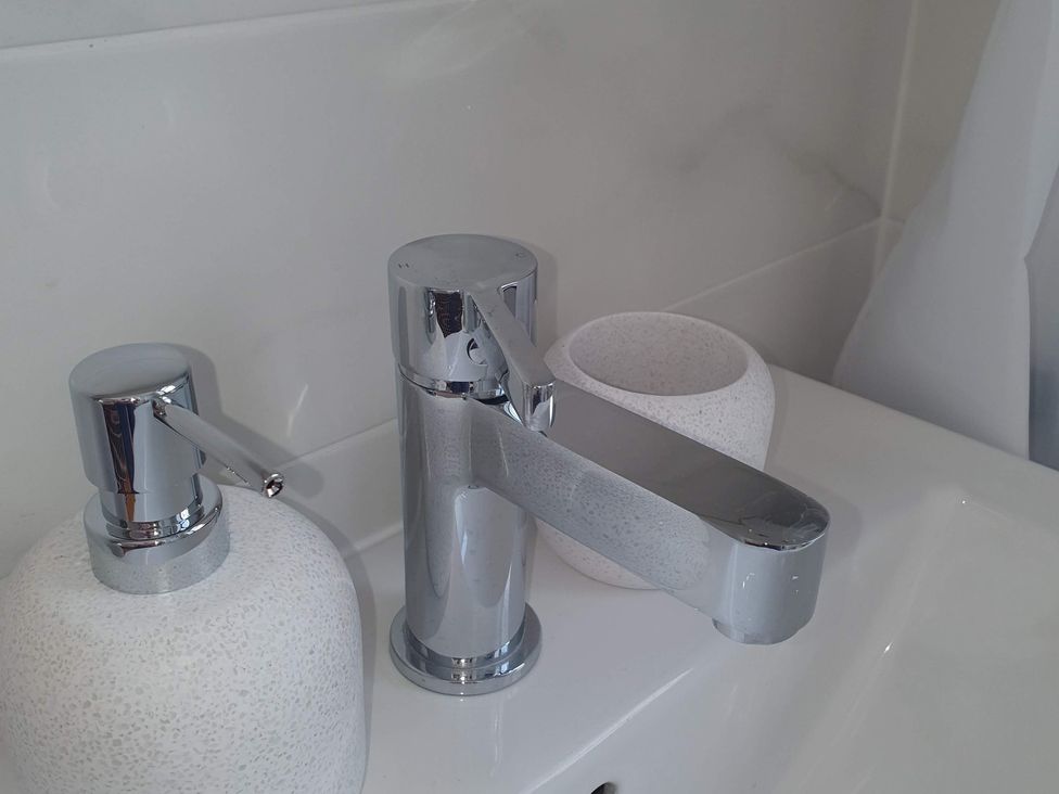 A faucet and soap dispenser on a sink in Kinamara Ensuite Room