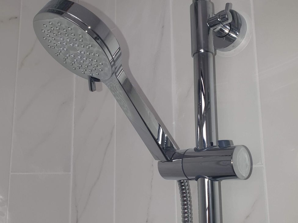A showerhead and arm in a bathroom at Kinamara Ensuite Room
