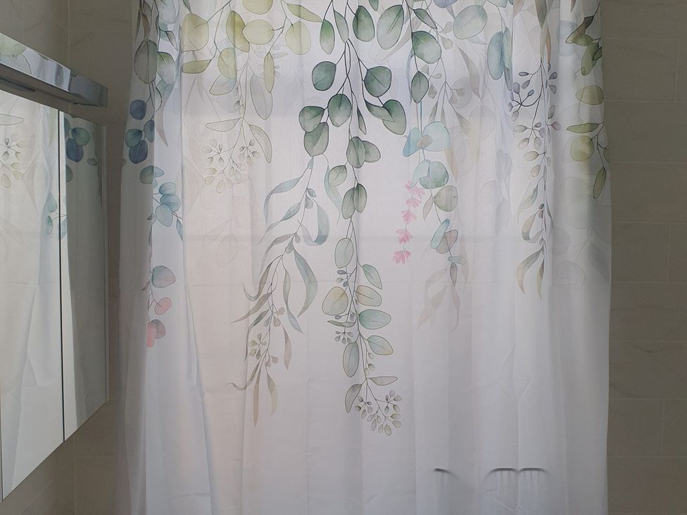 A bathroom with a shower curtain and a mirror at Kinamara Ensuite Room