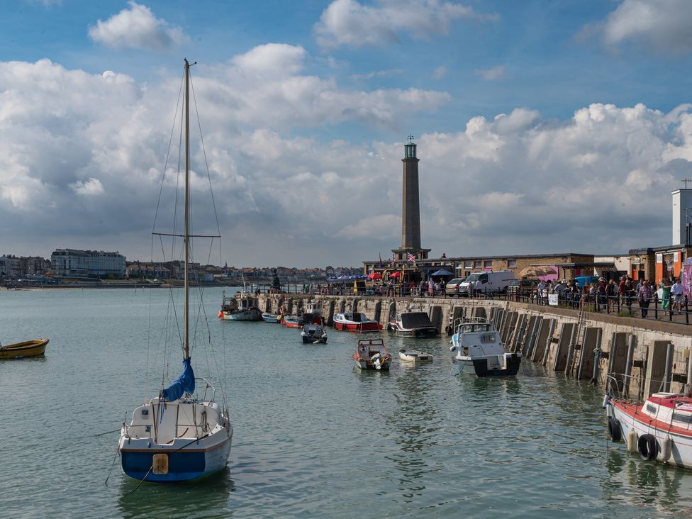 A view of boats and a lighthouse at a harbor with people at The Old Barn in 