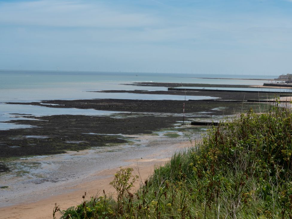 A beach with sand and grass along the shore at Kinamara Ensuite Room