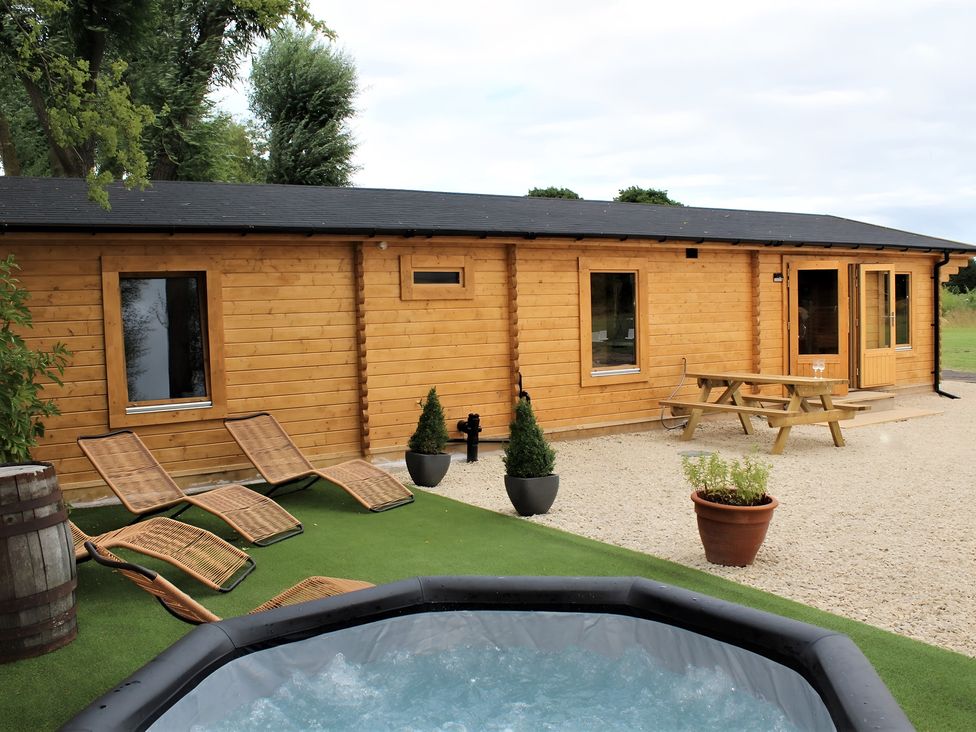 A log cabin with a hot tub and picnic bench at Cotswold Nights Away Evesham