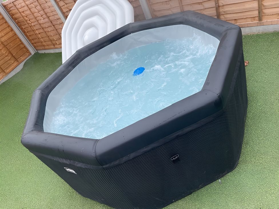 A hot tub filled with water in a garden at Cotswold Nights Away in Evesham