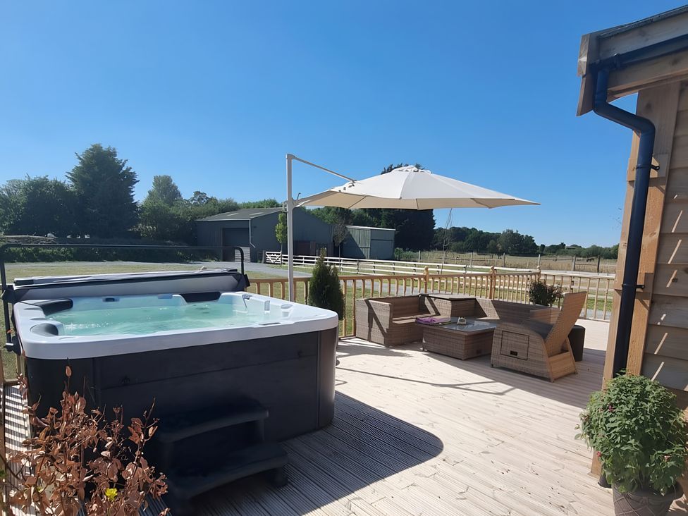 A patio area with a hot tub and outdoor furniture at Fox Lodge in York
