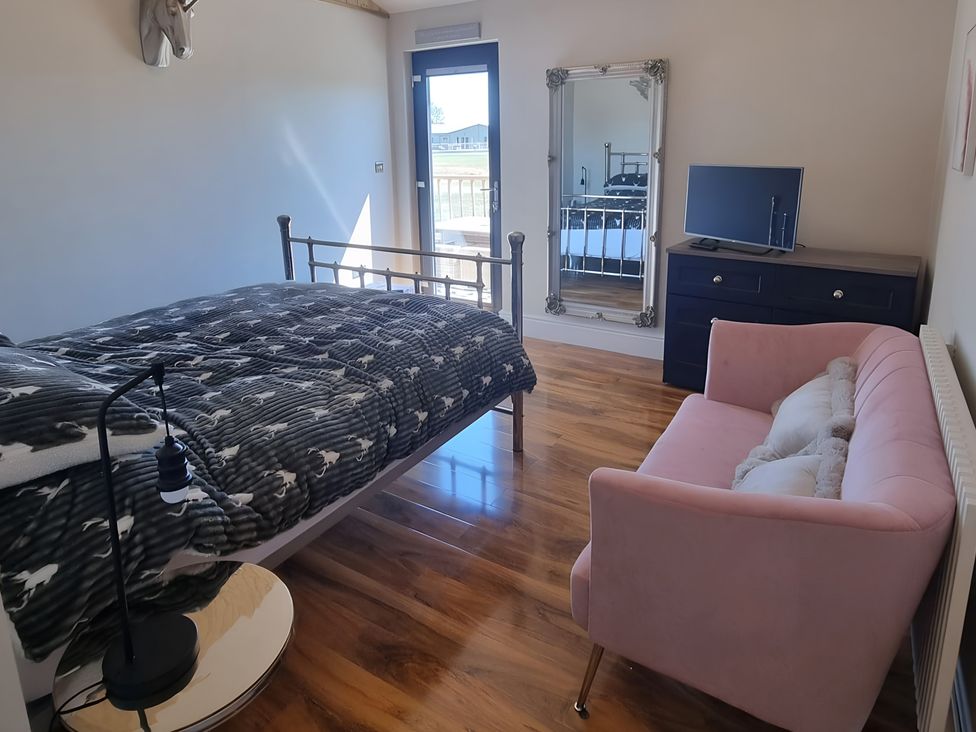 A bedroom with a bed, mirror, television and sofa at Fox Lodge in York