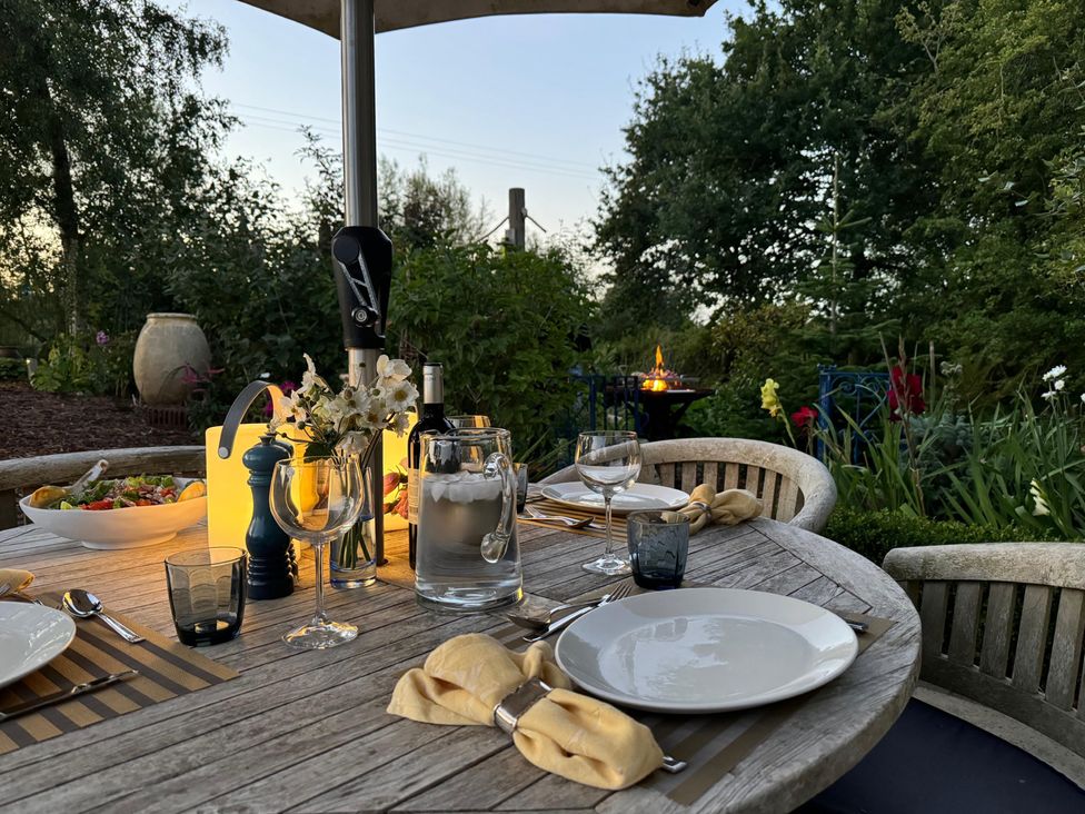 An outdoor dining table set with plates and glasses at Christmas Cottage in Shipston-on-Stour