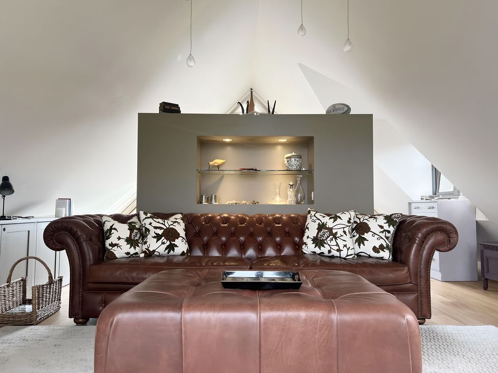A living room with a sofa, coffee table and shelves at Christmas Cottage in Shipston-on-Stour