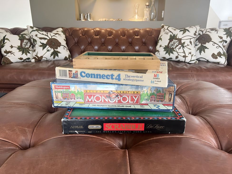 Board games stacked on a table in a living room at Christmas Cottage in Shipston-on-Stour
