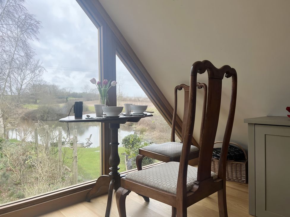 A dining room with a table and chairs by a large window at Christmas Cottage in Shipston-on-Stour