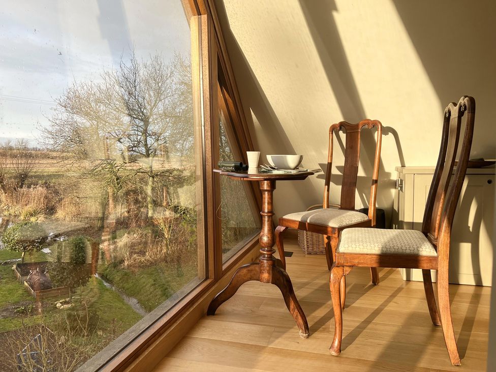 A table and two chairs near a window at Christmas Cottage in Shipston-on-Stour