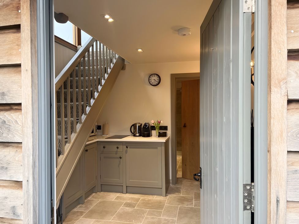 A kitchen area with appliances and stairs at Christmas Cottage in Shipston-on-Stour