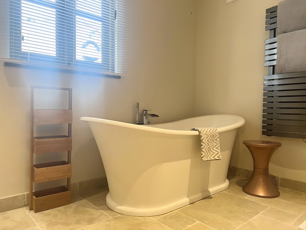 A bathroom with a bathtub and towel rack at Christmas Cottage in Shipston-on-Stour