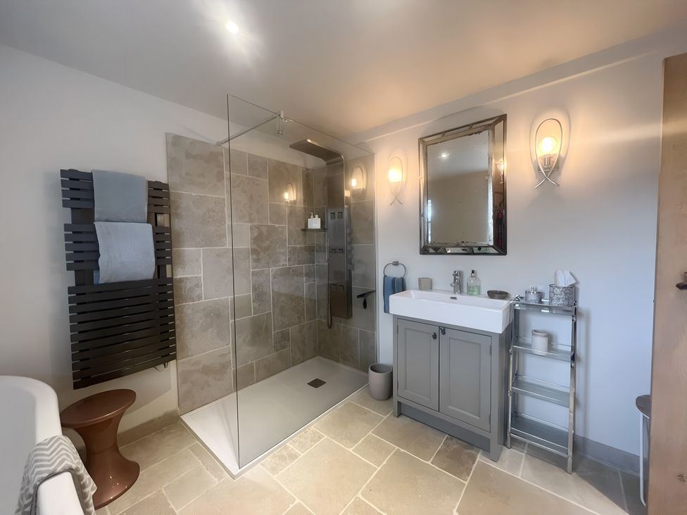 A bathroom with a shower, wash basin, and mirror at Christmas Cottage in Shipston-on-Stour
